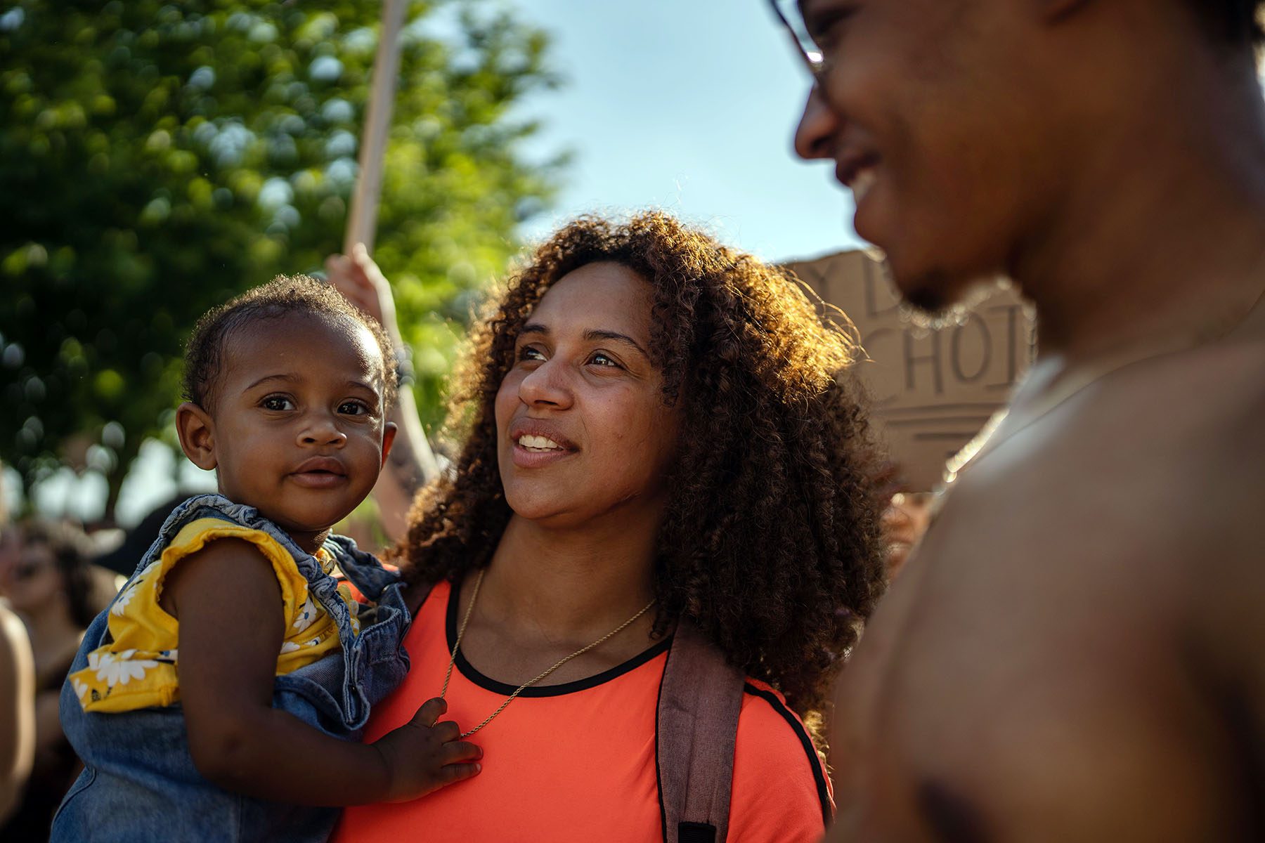 Nyla Harrison looks towards the Supreme Court as she holds her young daughter, Neeralena. Her partner stands next to the both of them, smiling as he looks at Nyla.