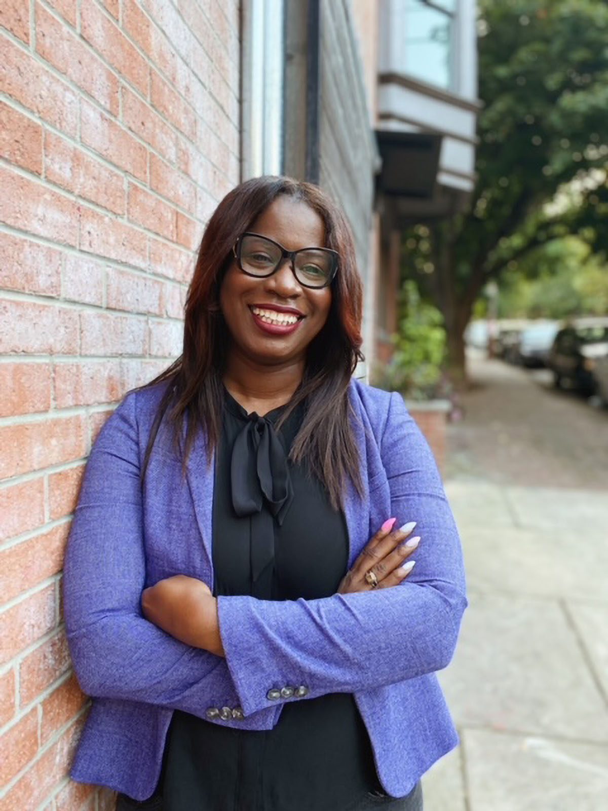 Smiling portrait of Atiyah Harmon leaning against a brick wall