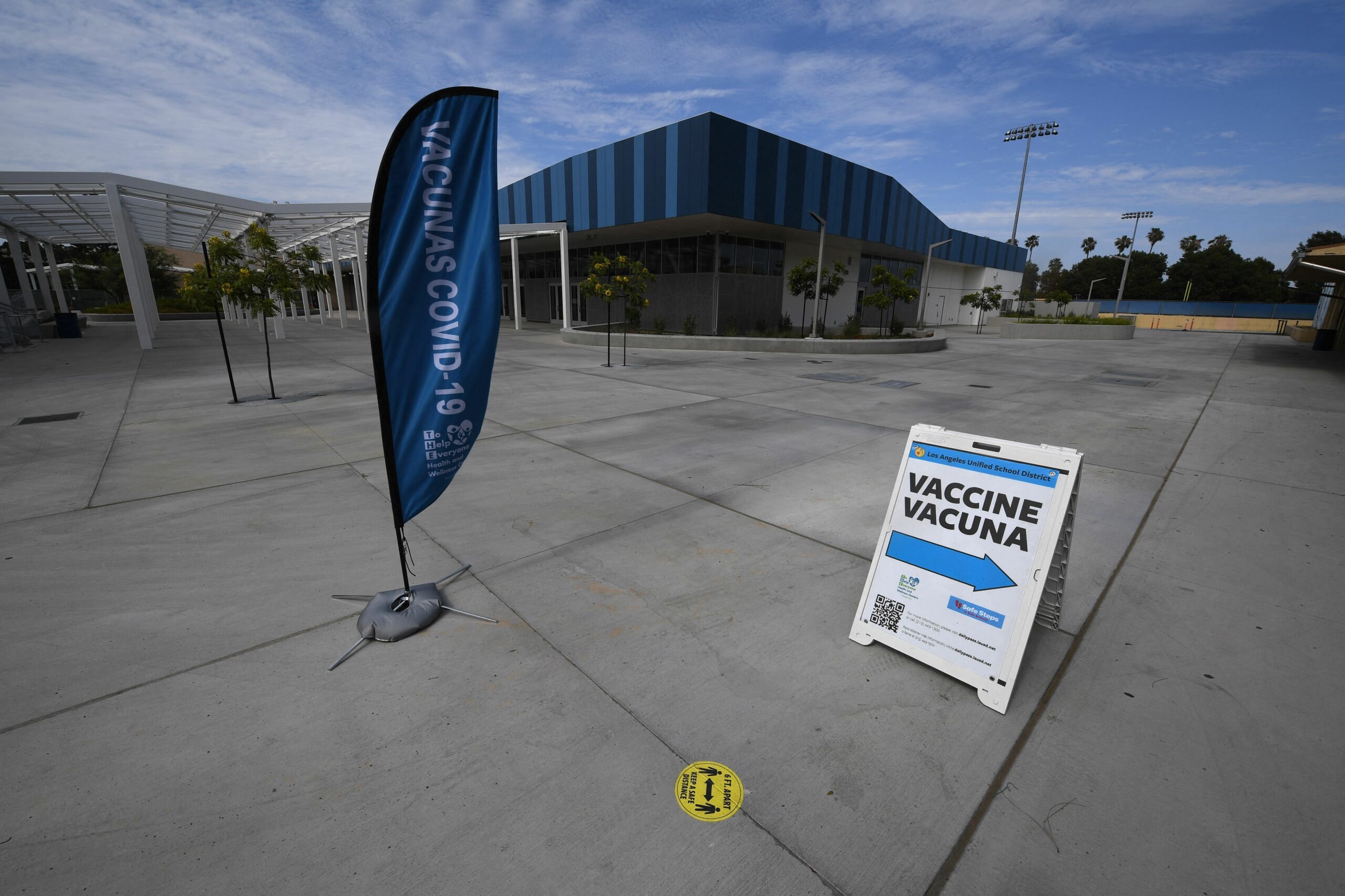 A sign points to a COVID-19 vaccination clinic in an empty parking lot.