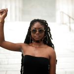 Aalayah Eastmond raises her fist as she poses for a portrait on the steps of the Lincoln memorial.
