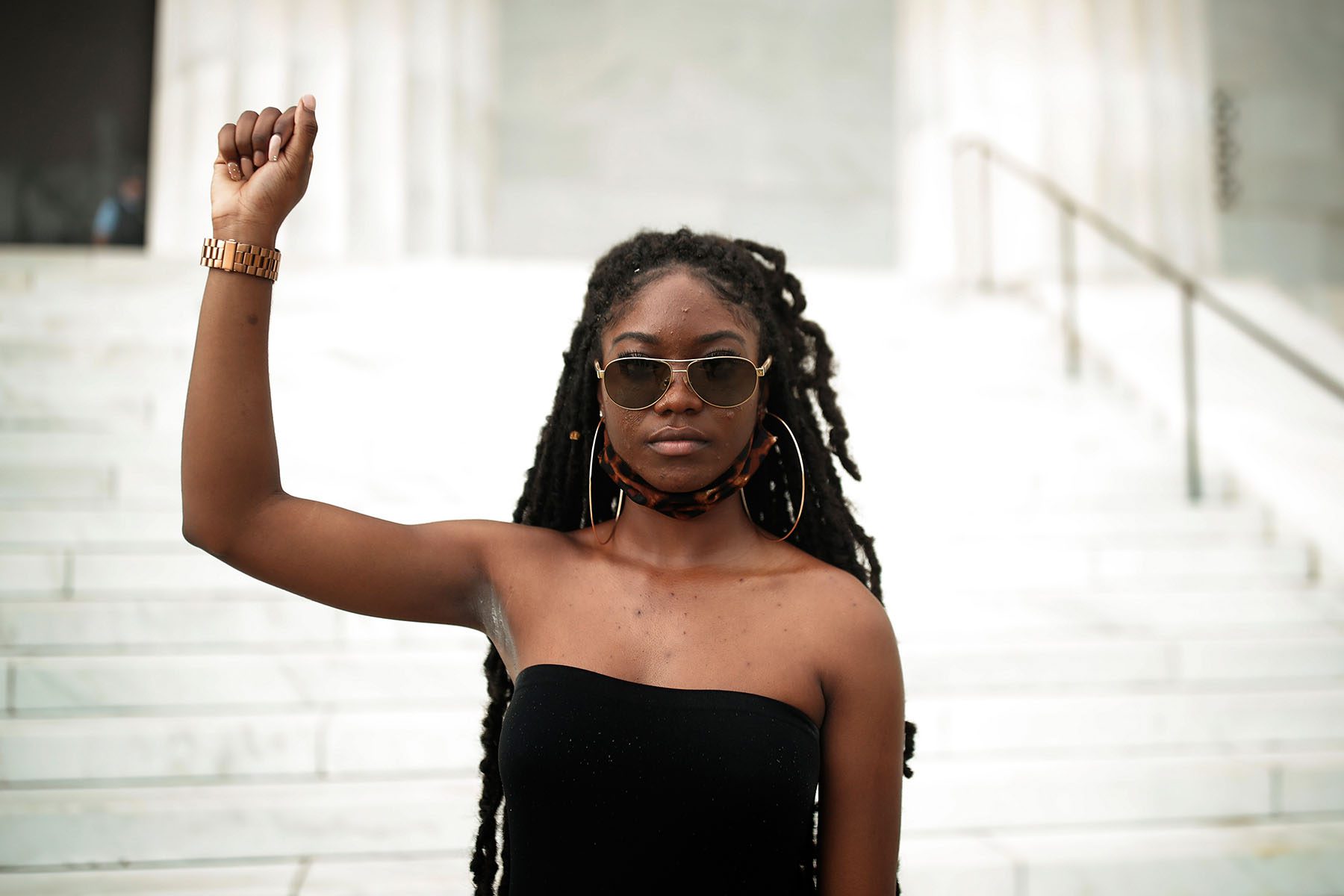 Aalayah Eastmond raises her fist as she poses for a portrait on the steps of the Lincoln memorial.
