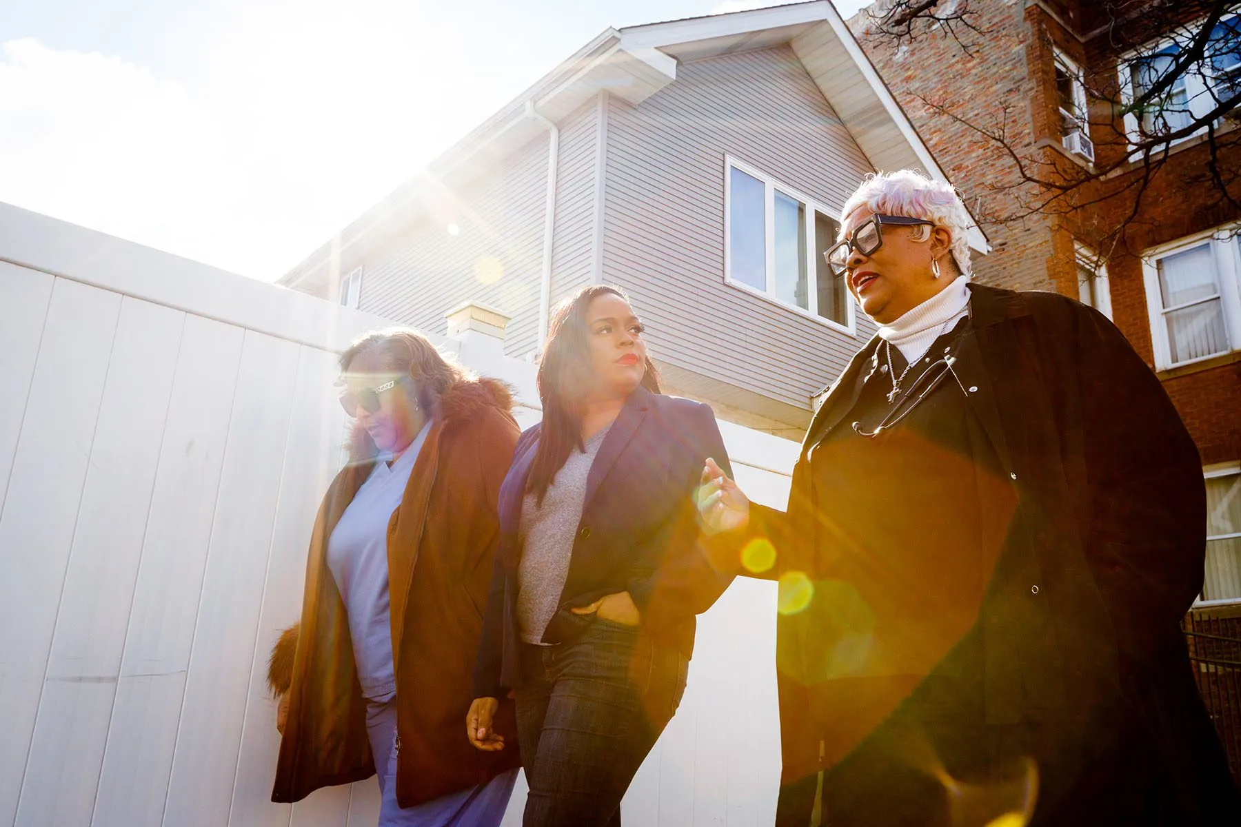 Kina Collins walks and speaks with two community members.