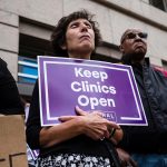 An activist seen holding a placard that says keep clinics open during a protest.