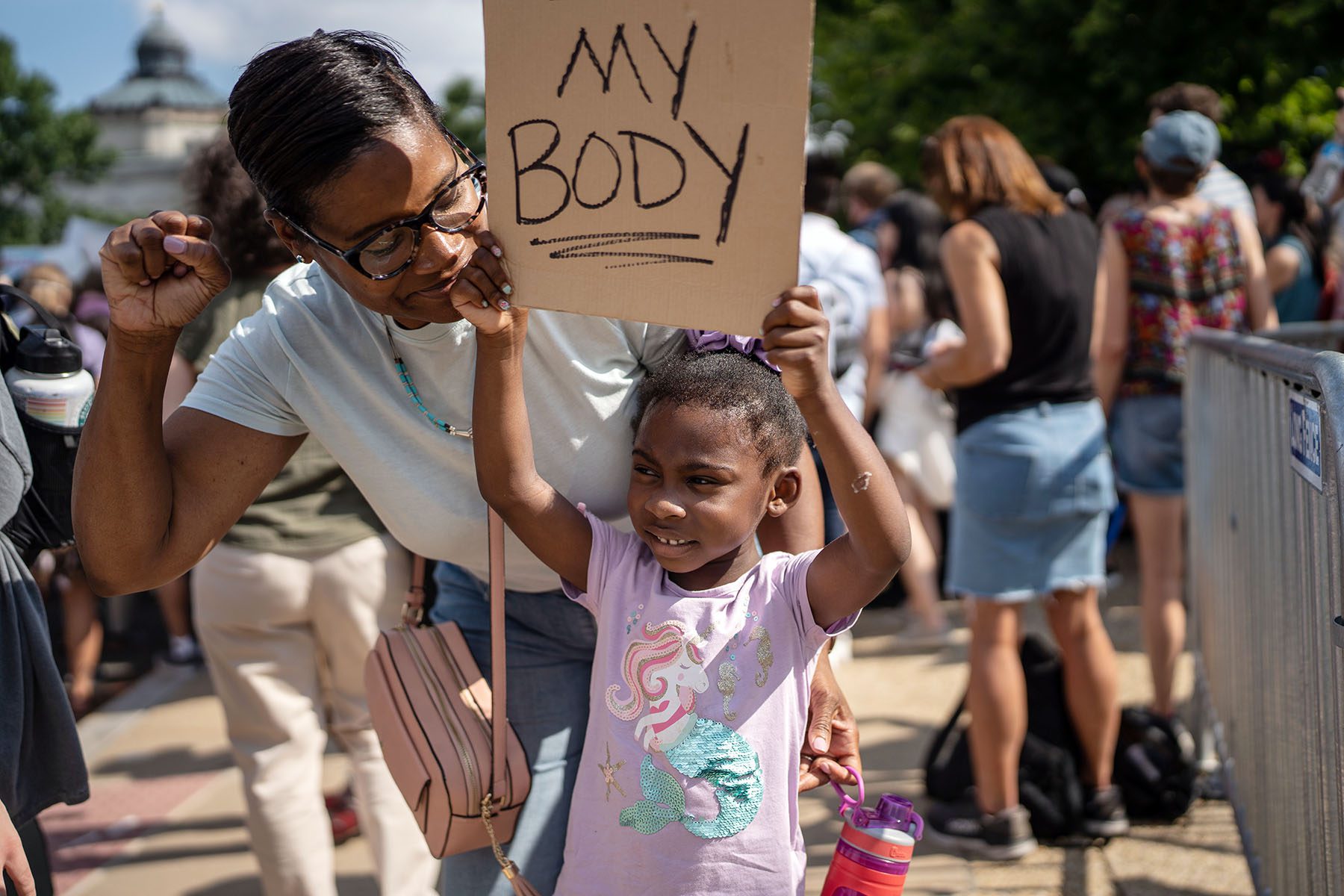 Roxanne Brown smiles as she looks at her daughter. Her daughter is holding a sign that reads "My body."