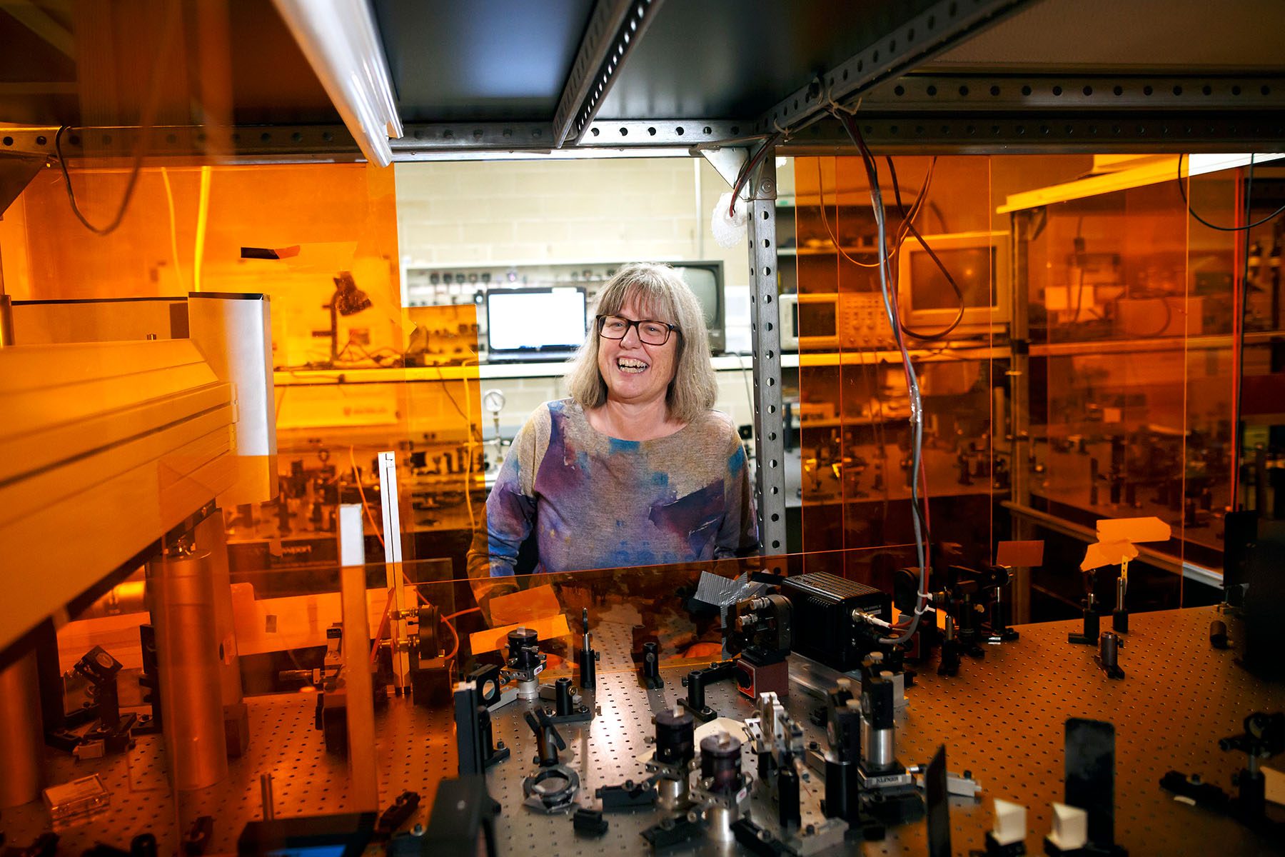 Professor Dr Donna Strickland smiles as she points to instruments in her lab.