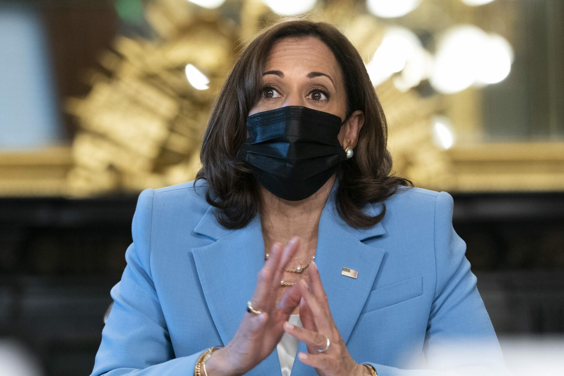 Vice President Kamala Harris wears a blue suit and black mask as she speaks at an event.