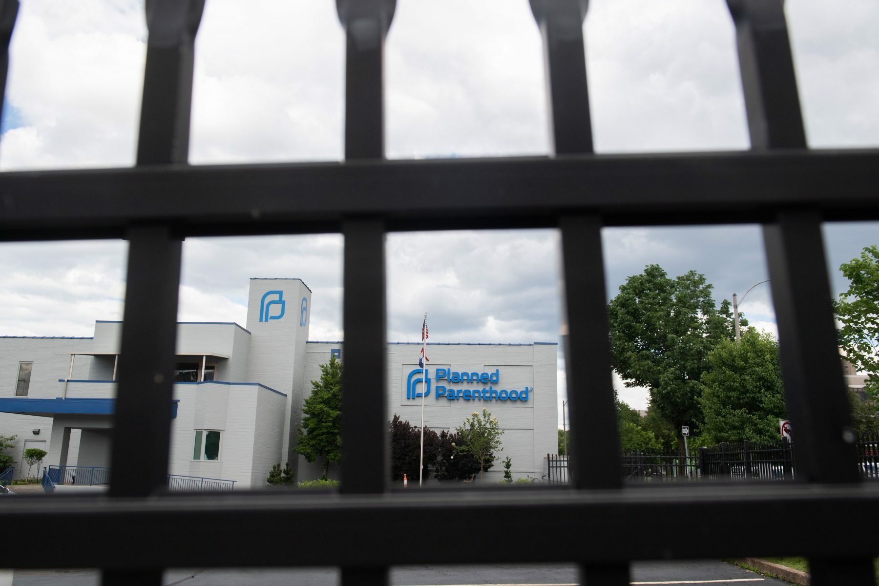 A fence in the foreground with a Planned Parenthood building in the background.
