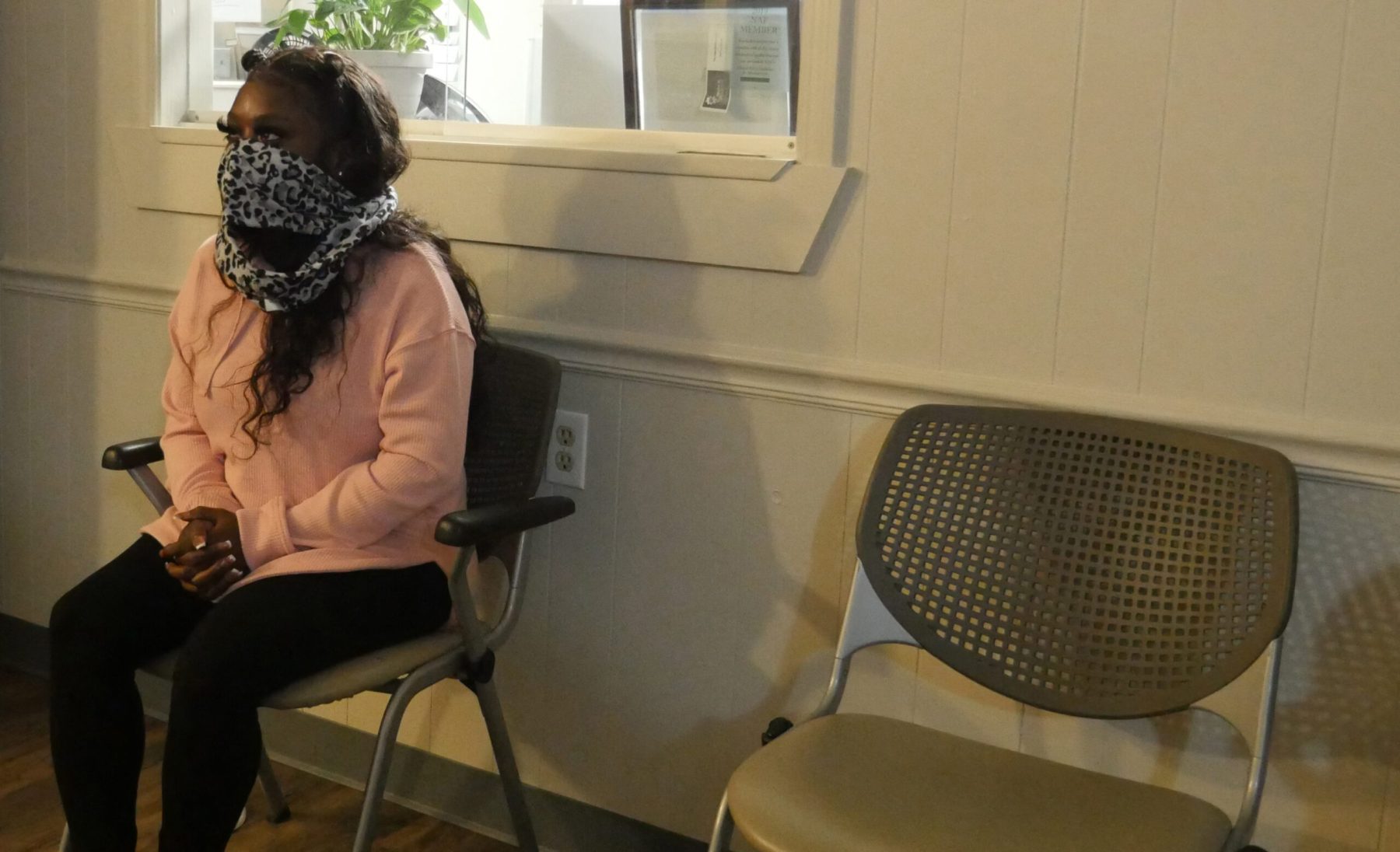 A woman sits in a chair in an abortion clinic waiting room.