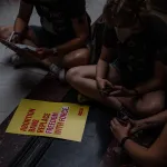 protesters sit around a yellow sign for abortion rights inside the indiana state capitol in indianapolis