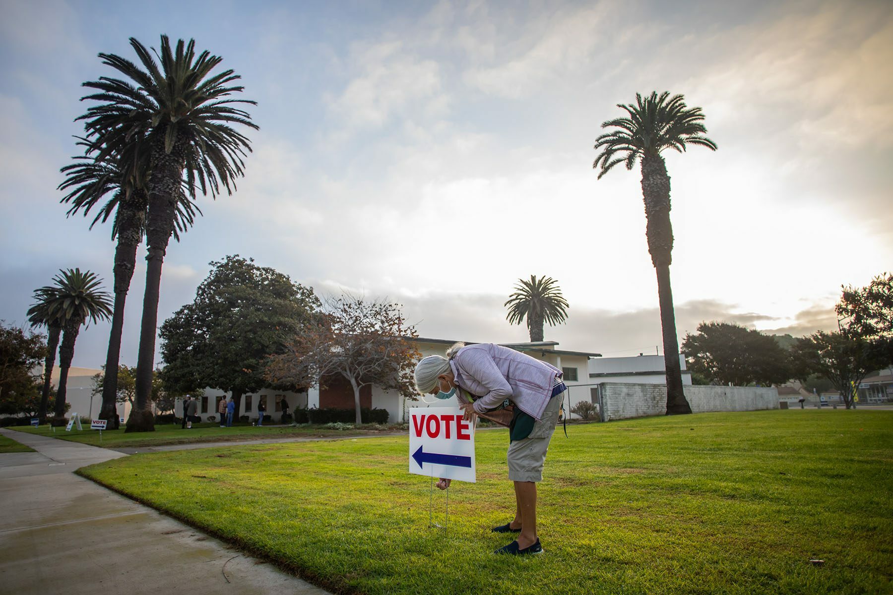 A woman arranges a voting sign near the Main Street Branch Library vote center in the early morning.