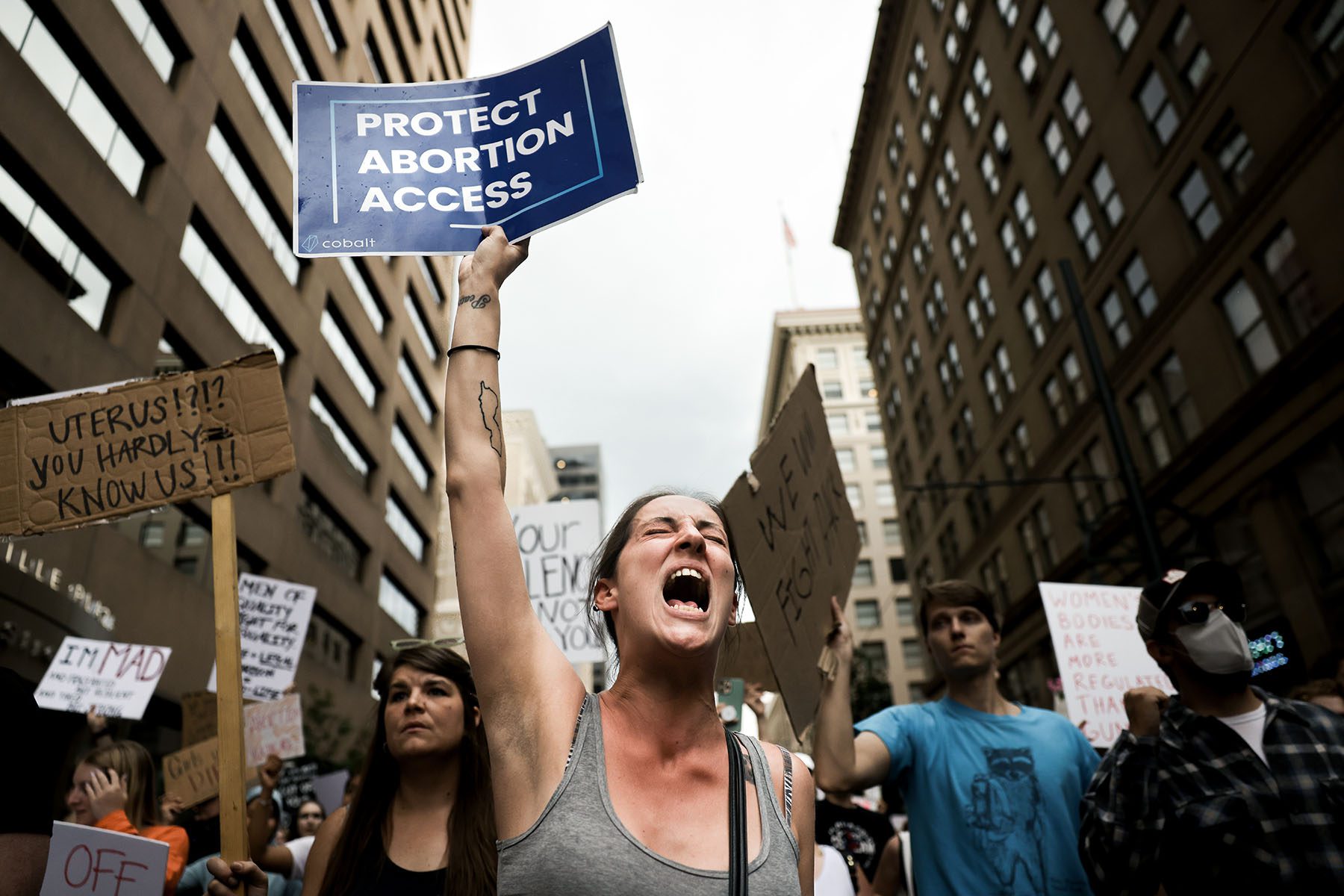 A demonstrator holds up a sign that reads "Protect Abortion Access" while chanting slogans during a protest.