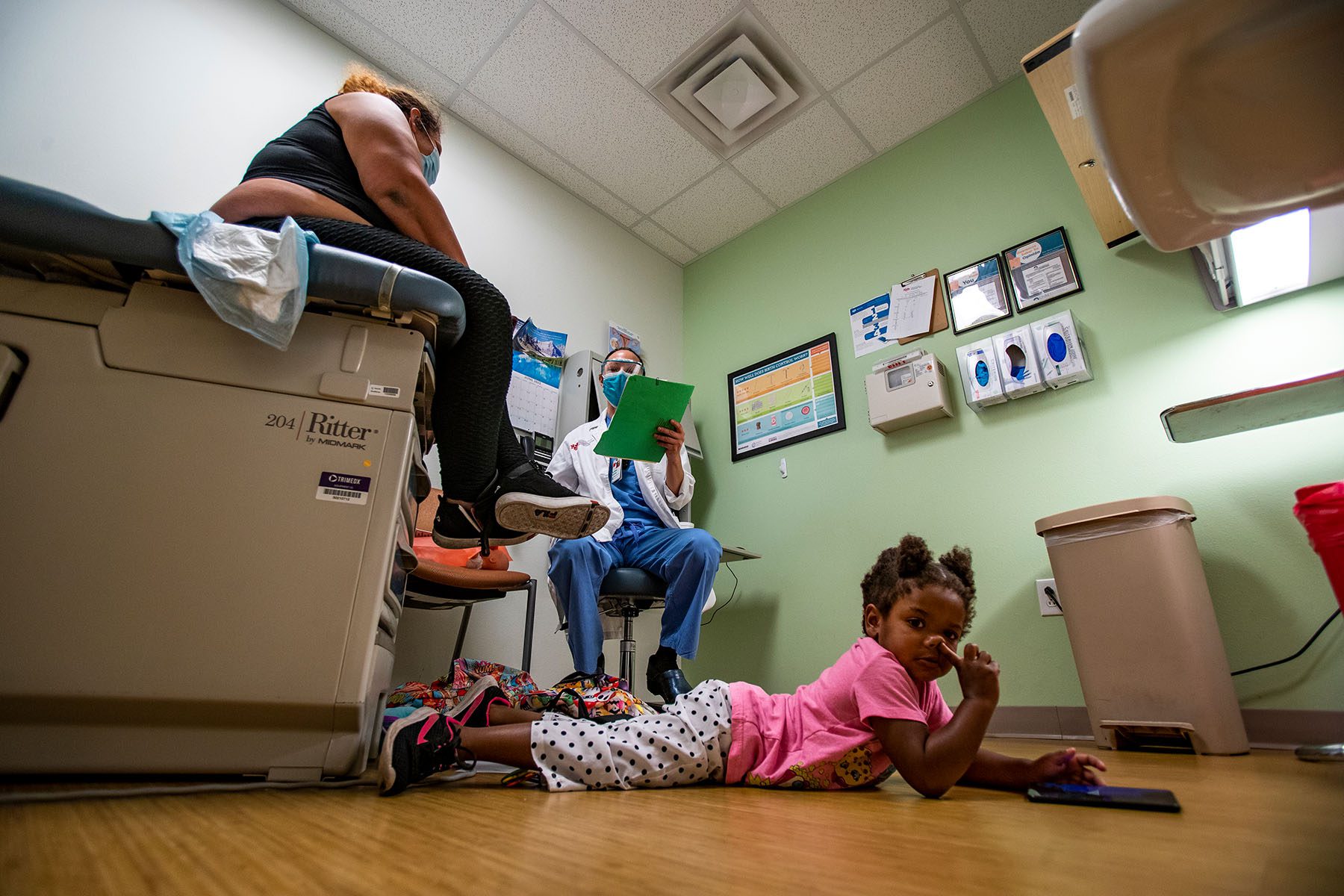 A doctor discusses the procedure for a medication abortion with a patient while the patient's daughter sits on the floor and plays.