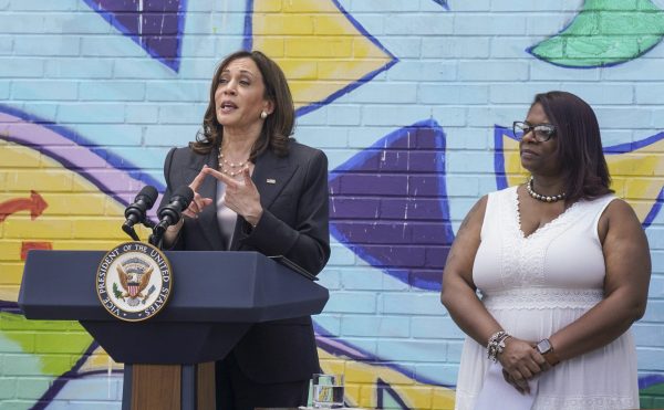 Kamala Harris talks in front of a colorful mural; assistant Pittsburgh city clerk Kimberly Clark-Baskin stands to her side
