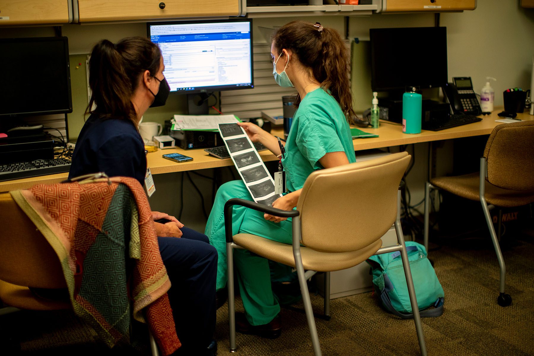 A family physician and her resident look over an ultrasound.