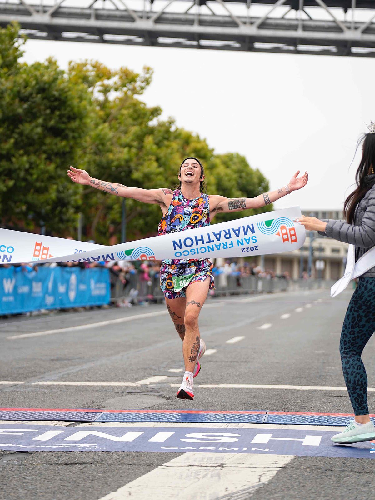 Cal Calamia, in colorful running gear, crosses the finish line at the San Francisco Marathon