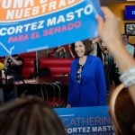 Sen. Catherine Cortez Masto attends a campaign event at a Mexican restaurant. Supporters hold campaign signs around her.