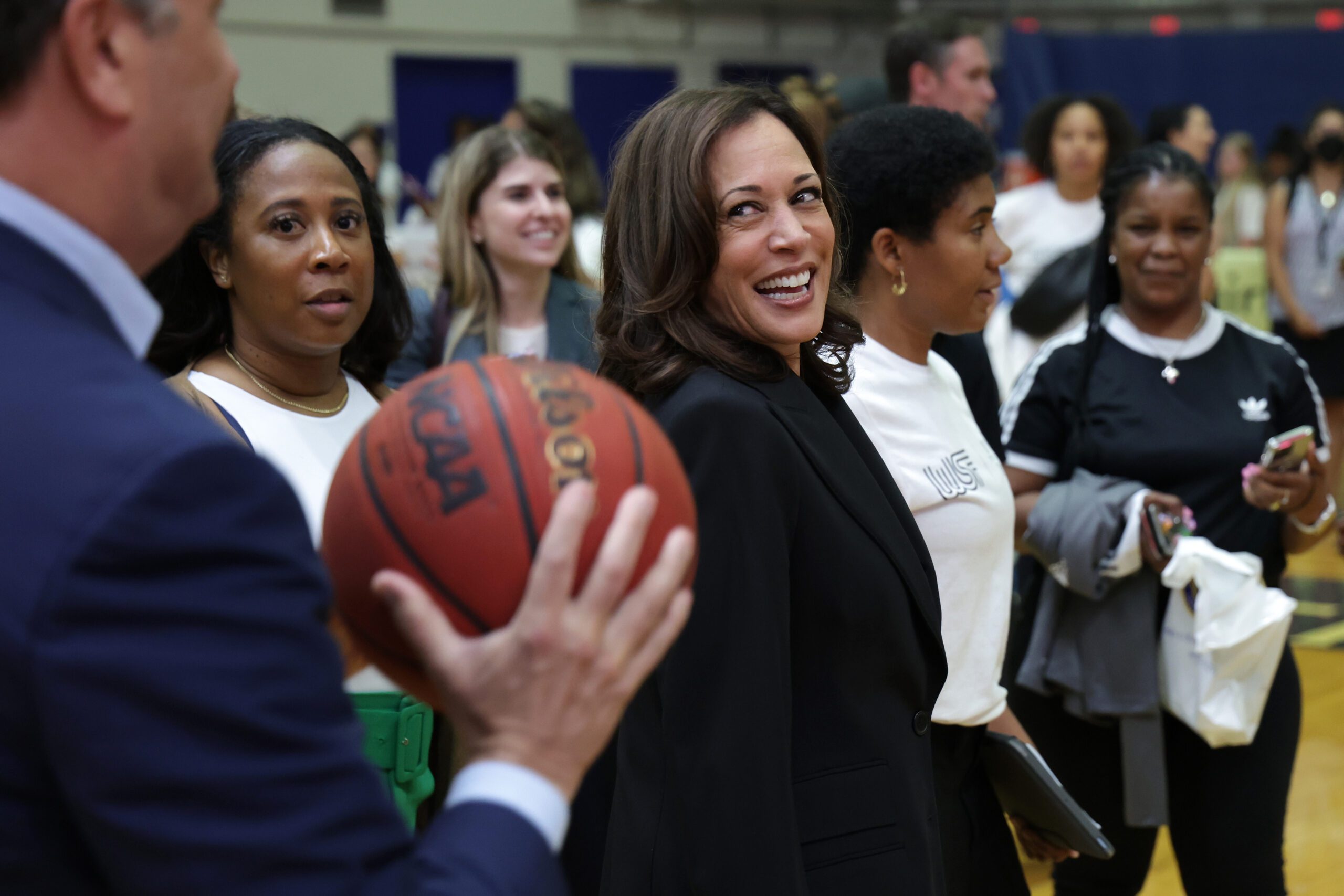 U.S. Vice President Kamala Harris looks on as her husband Doug Emhoff holds a basketball.
