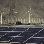 Solar panels and windmills in a desert.