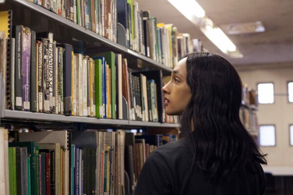 A trans woman looks at books in a college library