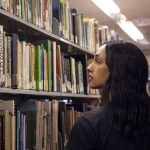 A trans woman looks at books in a college library