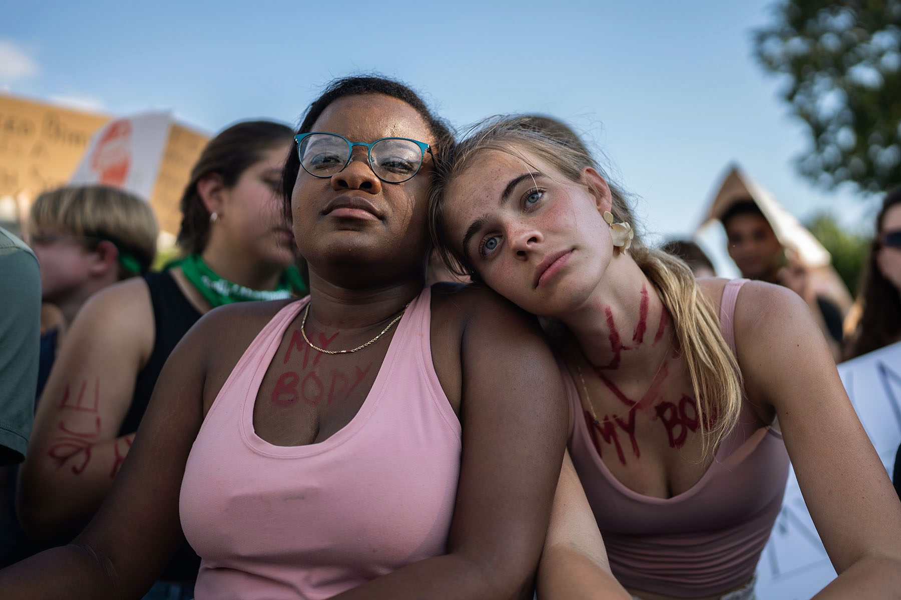 Two friends lean on one another as they look into the distance amidst a demonstration outside the Supreme Court.