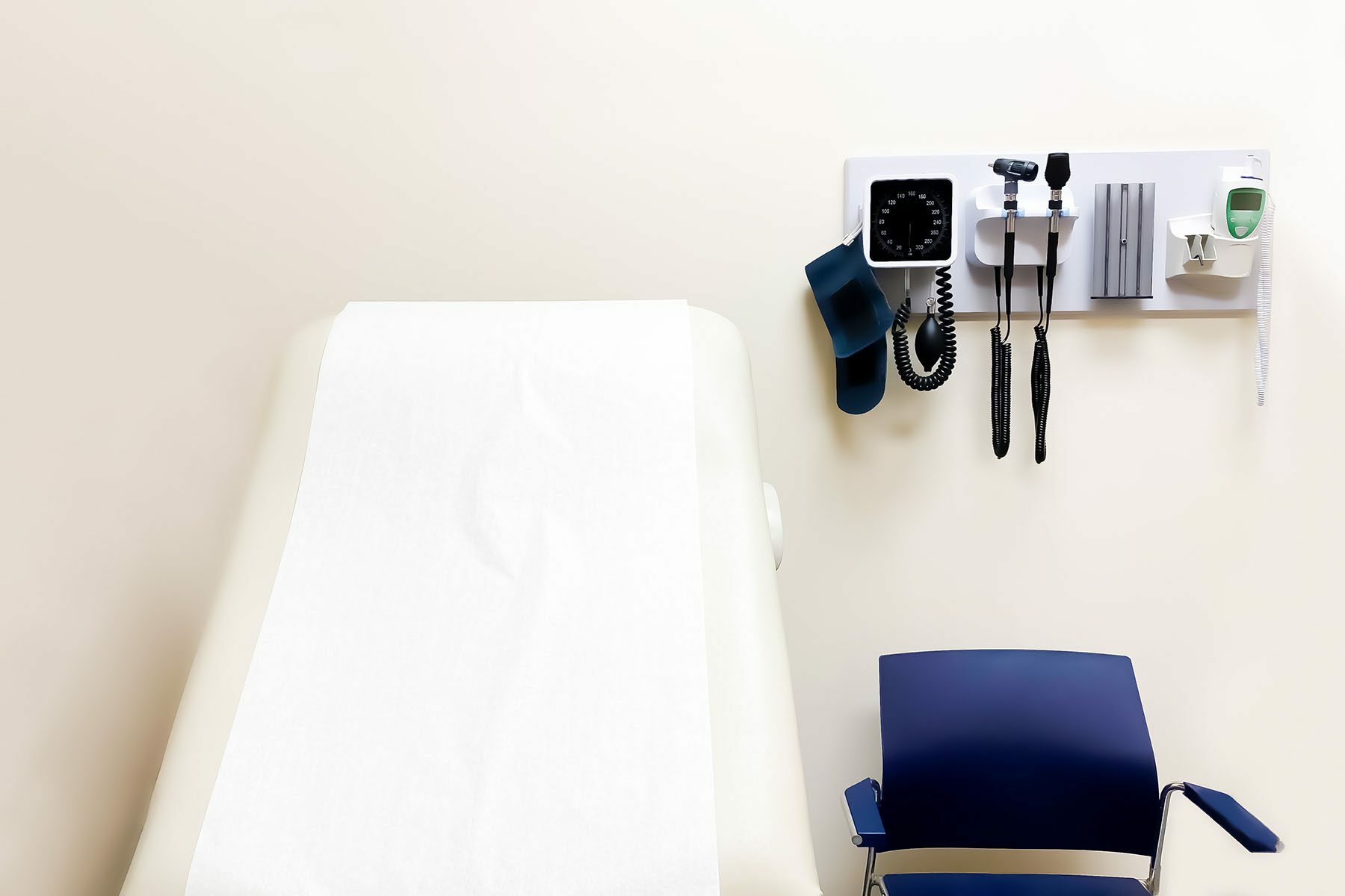 wall-mounted medical diagnostic equipment beside standard patient examination chair