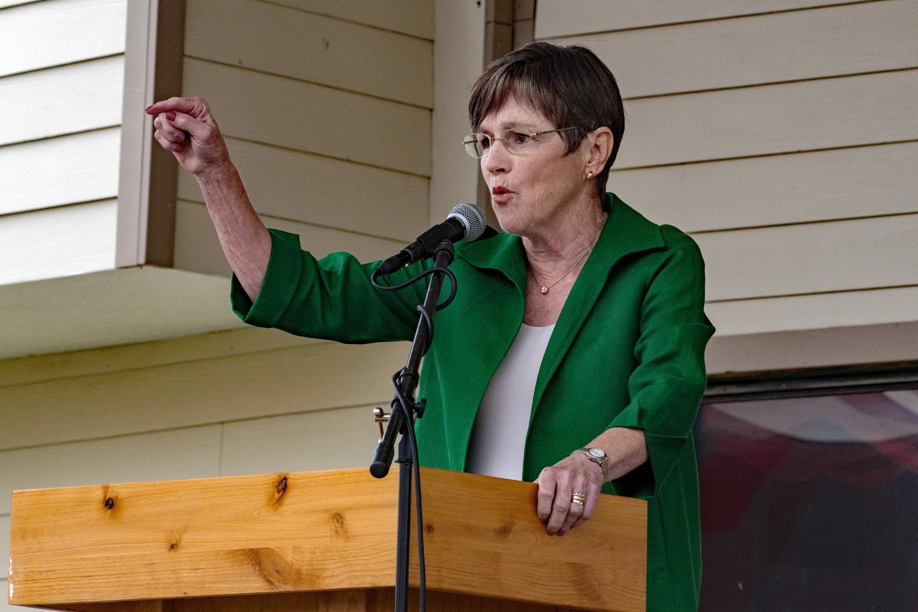 Georgia Gov. Laura Kelly gives a speech from a podium wearing a green shirt and pointing.