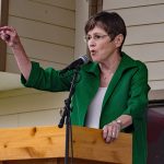 Georgia Gov. Laura Kelly gives a speech from a podium wearing a green shirt and pointing.