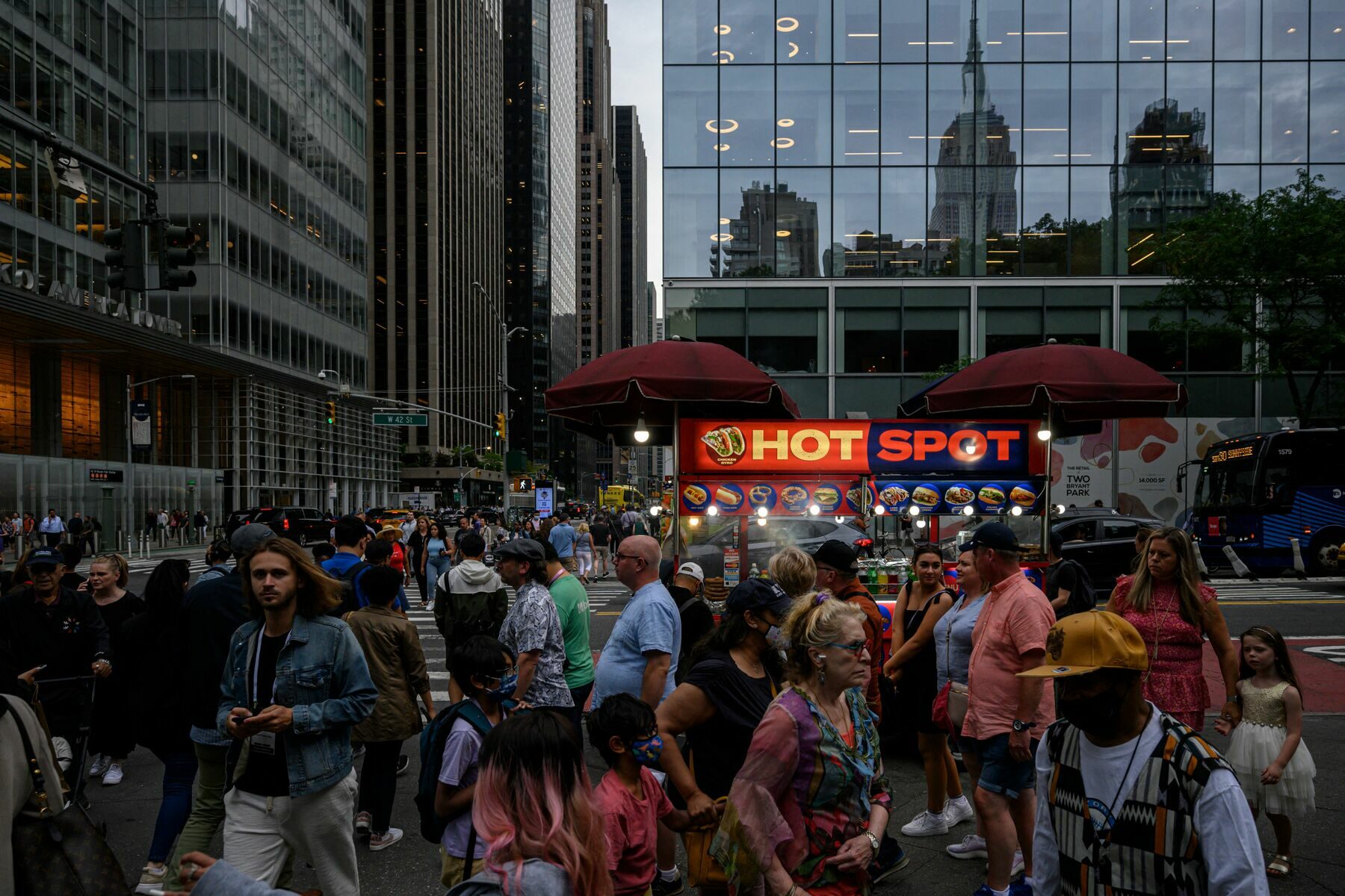 People make their way along a city street past a food vendor in New York.