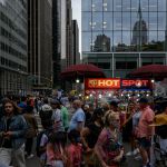 People make their way along a city street past a food vendor in New York.