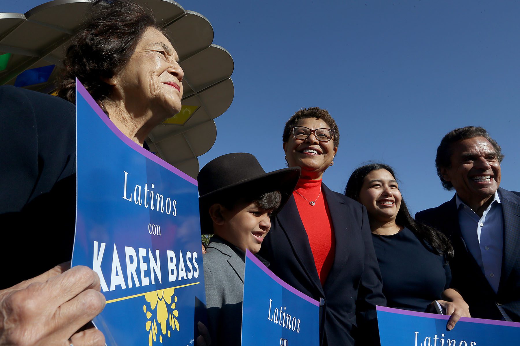 Karen Bass, her grandchildren, Dolores Huerta and Antonio Villaraigosa pose for a picture together at a campaign event. Huerta and Bass' grandchildren hold signs that reads "Latinos con Karen Bass."