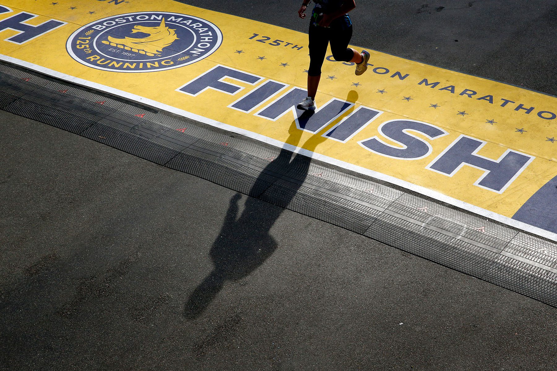 A runner casts a shadow as they cross the finish line of the 125th Boston Marathon.
