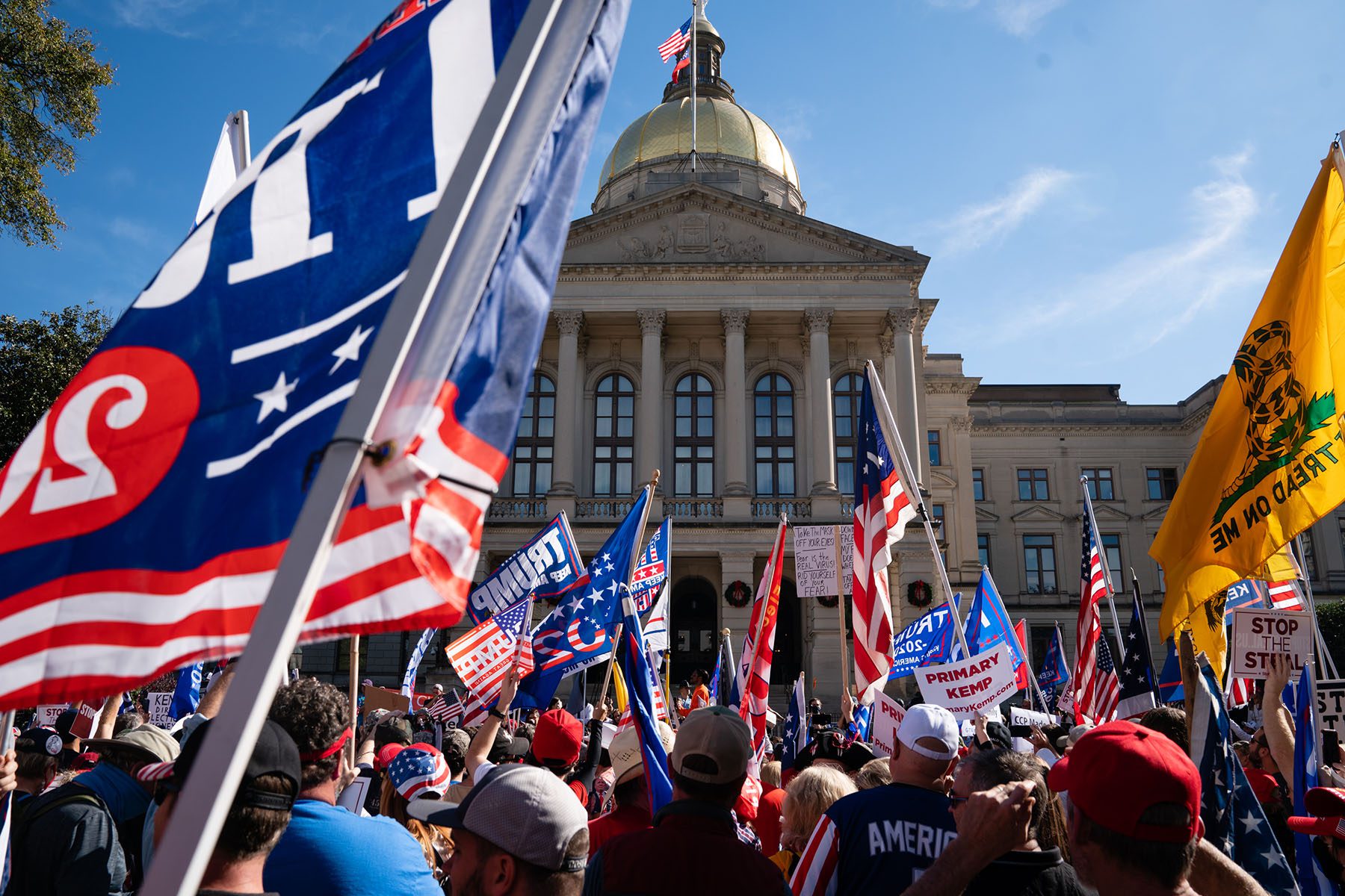 Demonstrators rally outside the Georgia State Capitol during a protest against the results of the 2020 Presidential election. They carry "Trump 2020" flag and signs that read "Stop The Steal."