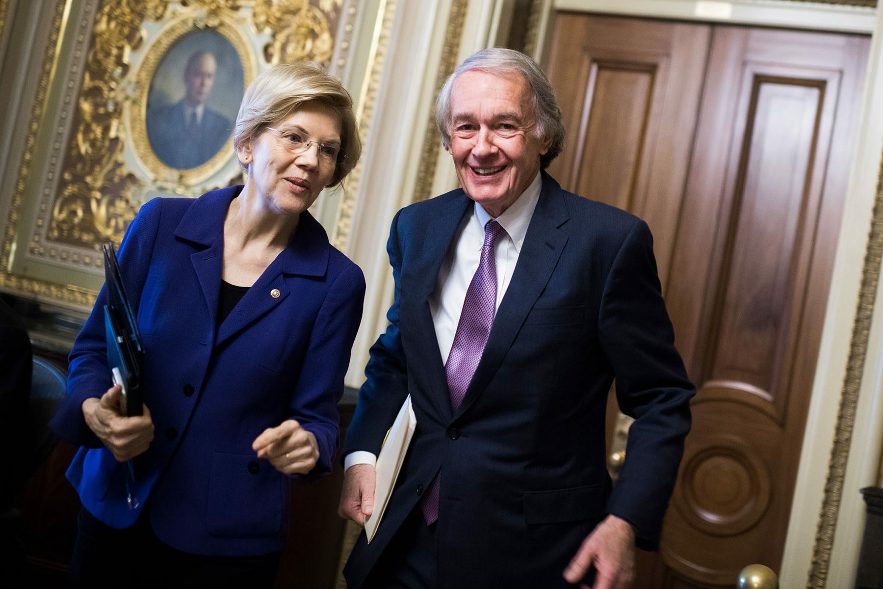 Sens. Ed Markey and Elizabeth Warren smile while speaking to each other on Capitol Hill.