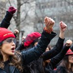 Women protest and sing songs with their fists in the air as Harvey Weinstein attends a pretrial session in New York City.