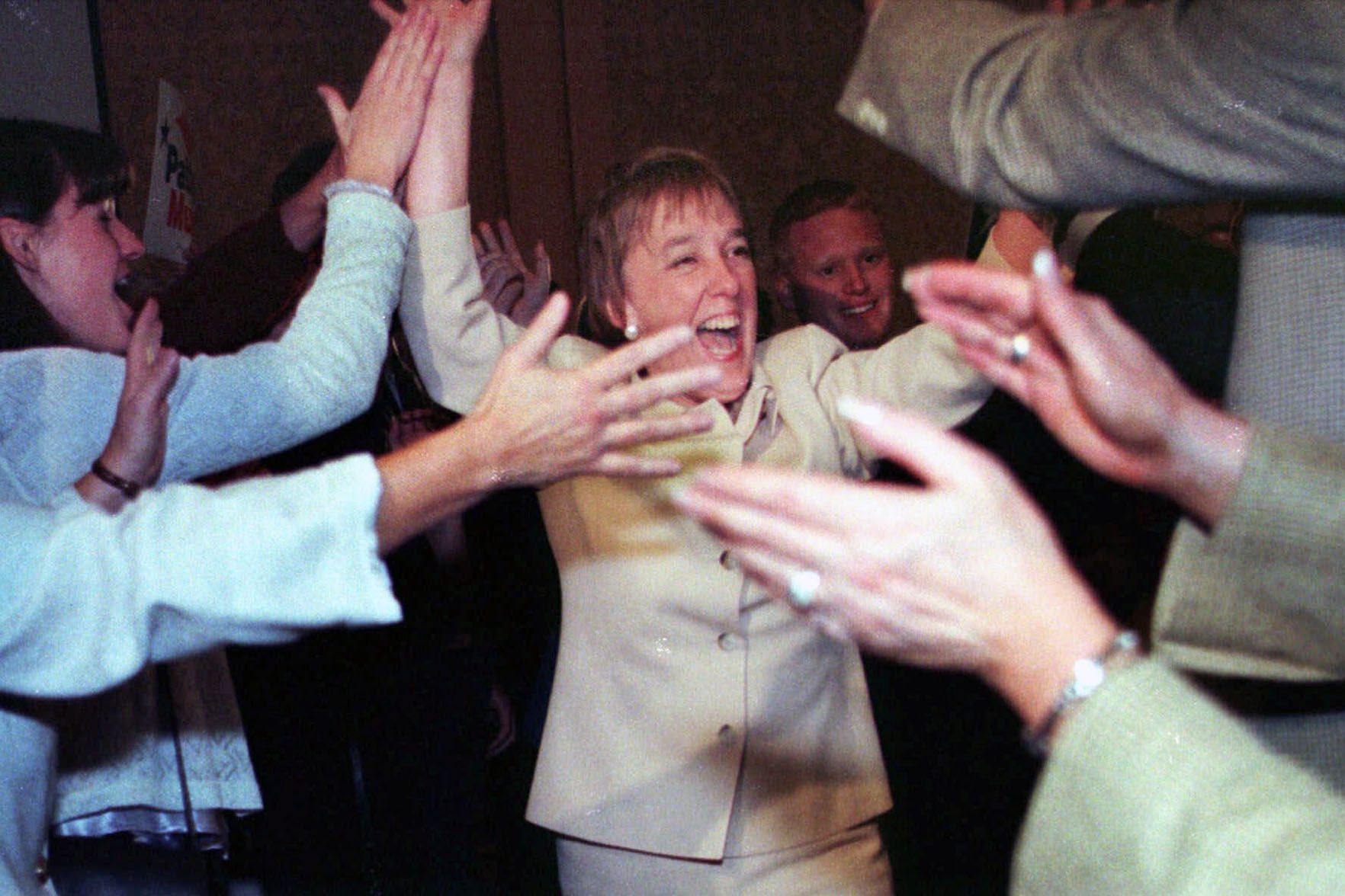 A smiling Patty Murray walks through a line of elated supporters.