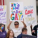 People hold colorful signs at a protest against Florida's Don't Say Gay bill