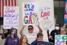 People hold colorful signs at a protest against Florida's Don't Say Gay bill
