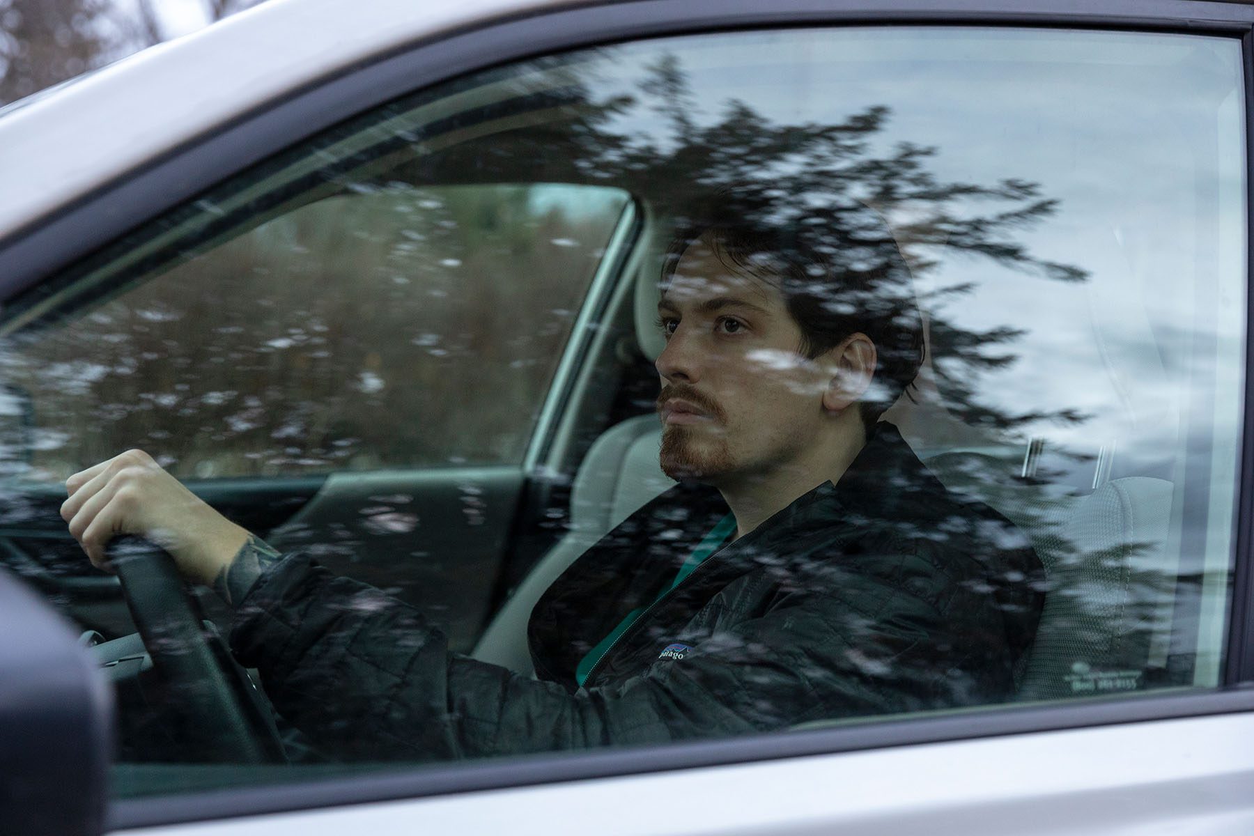 A travel ICU registered nurse sits inside his car.