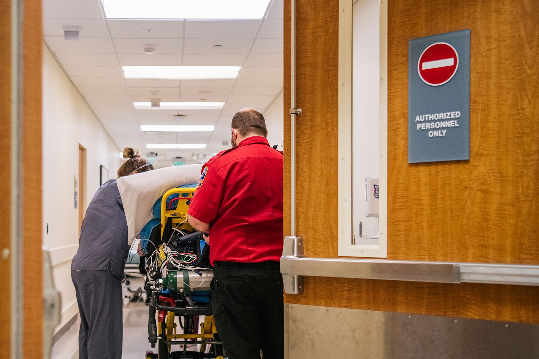 Emergency room nurses and EMTs tend to a patient in a hallway.