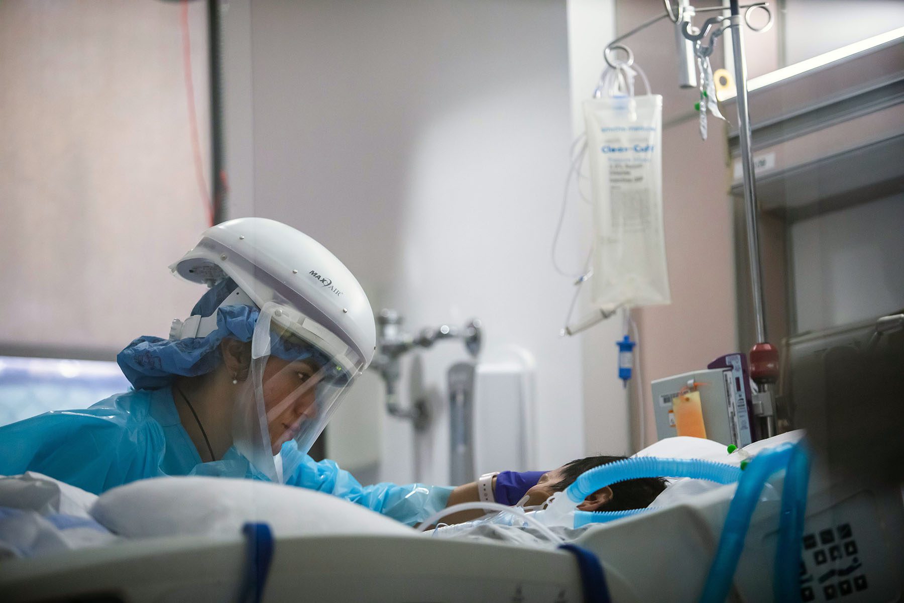 A nurse wearing PPE cares for a COVID-19 patient in an Intensive Care Unit.