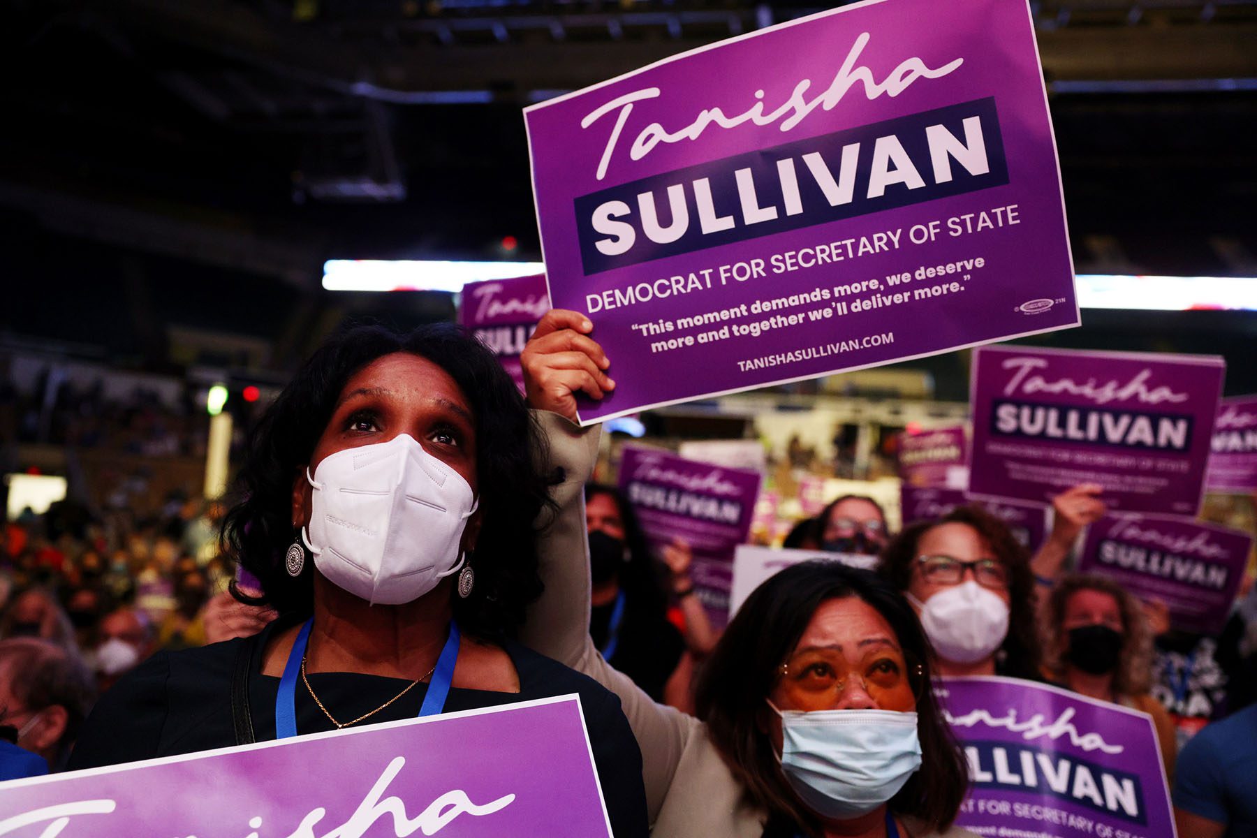 People holding signs in support of Tanisha Sullivan listen to her speak at the State Democratic Party Convention.