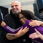 John Fetterman hugs a smiling supporter during a rally.