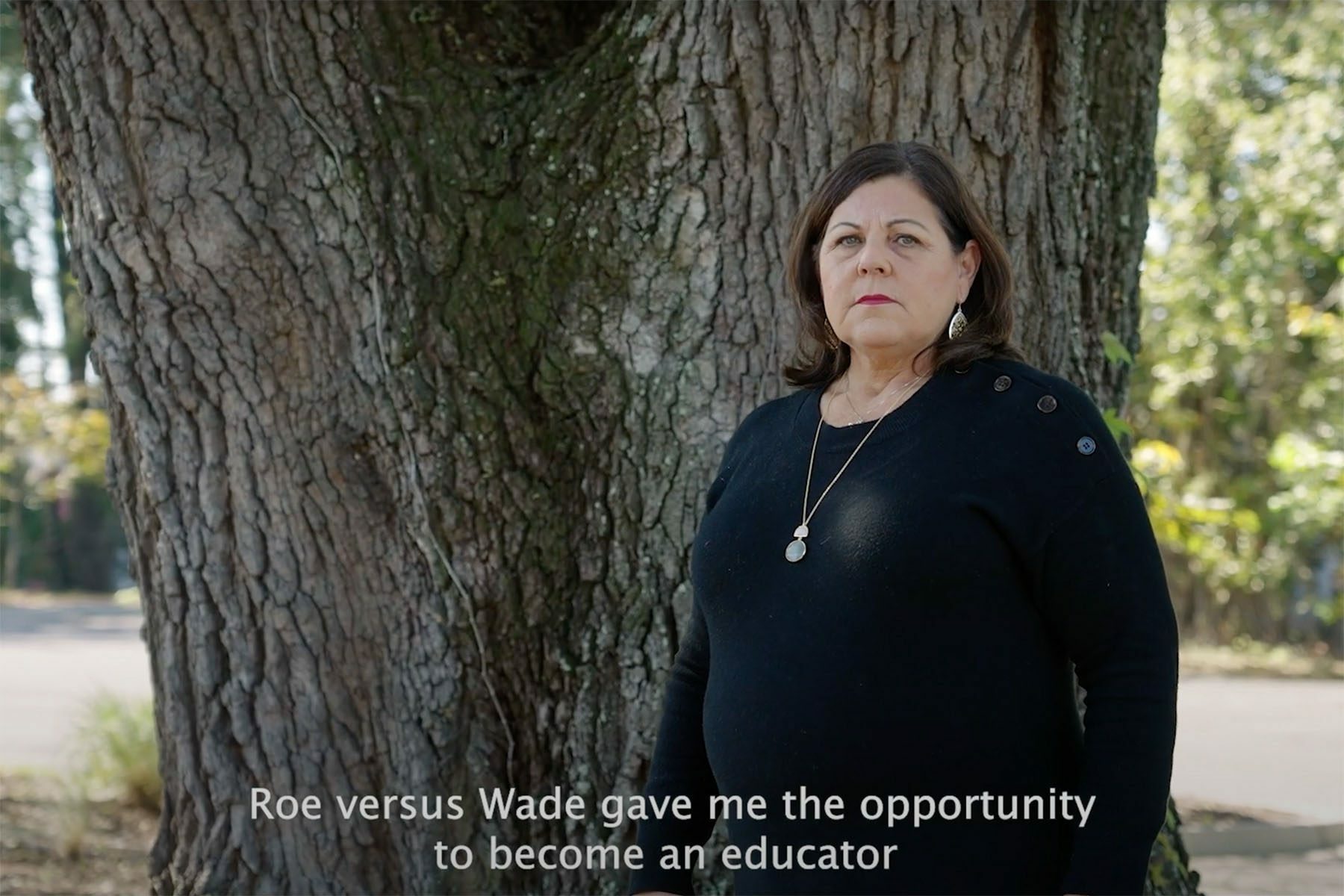 screenshot from South Carolina governor candidate Joe Cunningham’s newest ad in which a woman named Fran shares her abortion story. She is seen here standing near a tree and looking at the camera. The subtitles read 