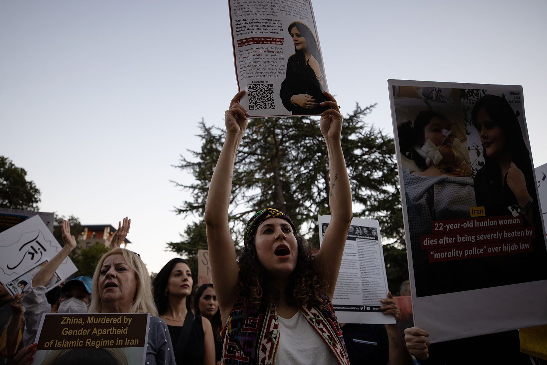 People hold signs and images of Mahsa Amini during a demonstration.