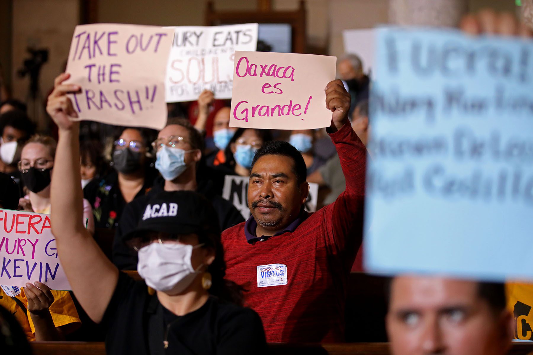 Protestors hold signs that read "Oaxaca es grande!" and "Take out the trash" at Los Angeles City Hall.