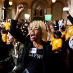 Protestors raise their fists and chant at the Los Angeles City council meeting.