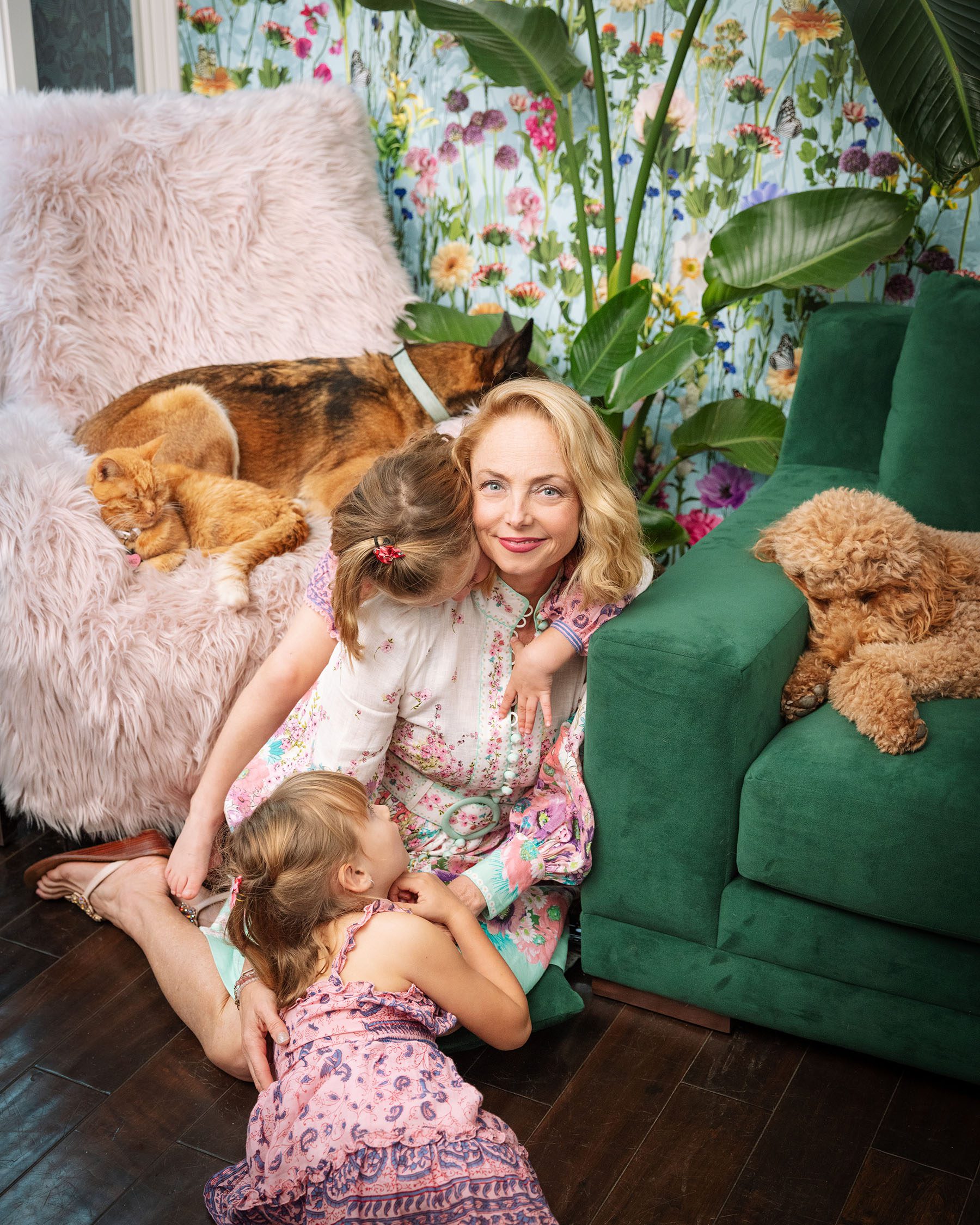 Louisette Geiss sits on the floor as her two daughters cuddle with her. Her dogs and her cat take naps on either sides of her.