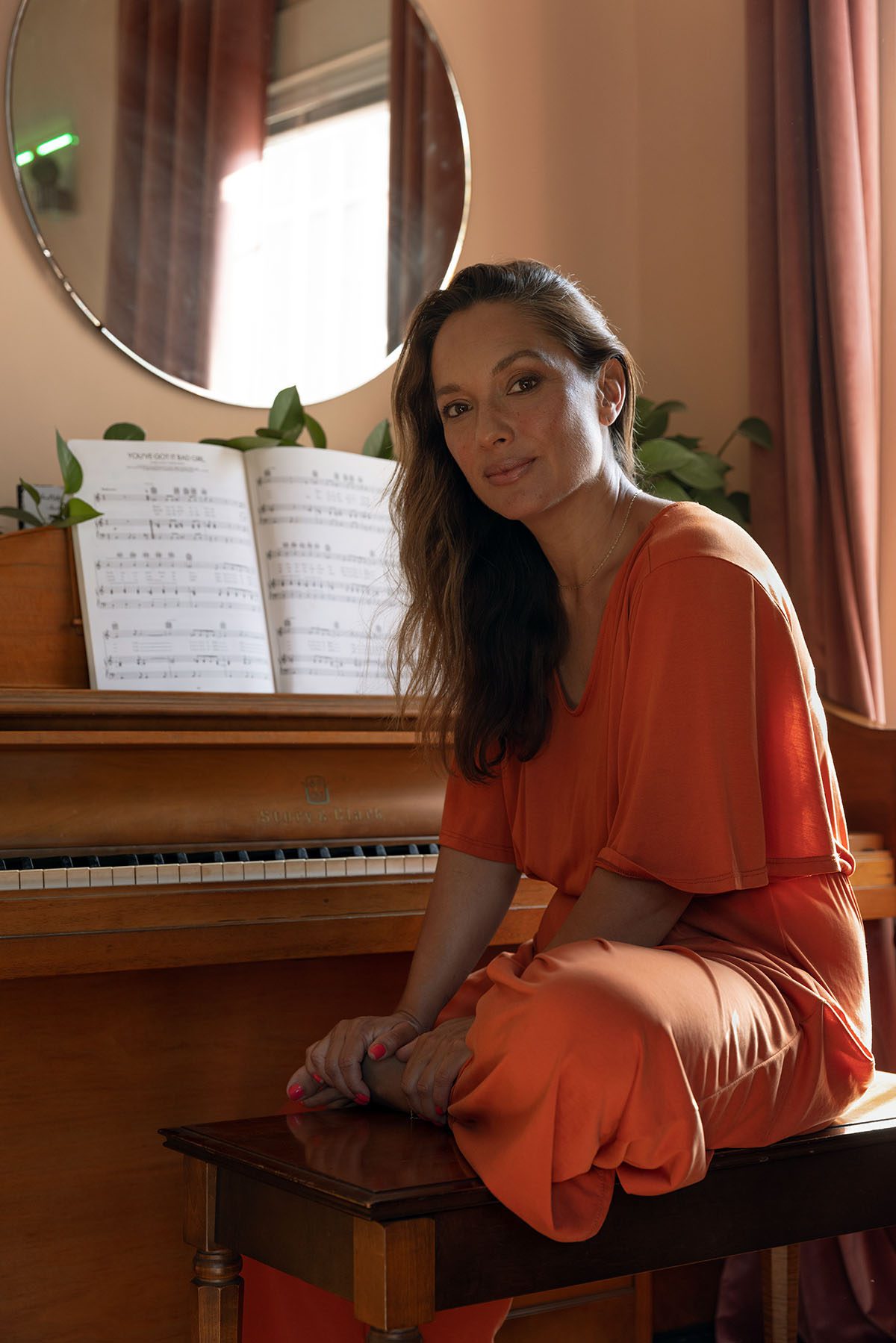 Larissa Gomes sits on a piano bench at her home.