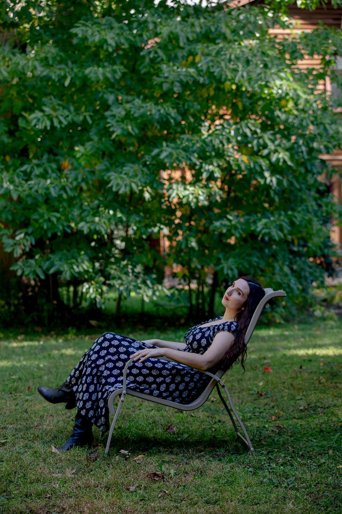 Sarah Anne Mass looks on while sitting in a chair in a garden.